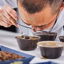 Quality control expert using a spoon to smell a coffee sample