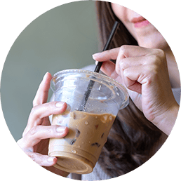 Woman about to sip from a straw to drink a to-go cup of iced coffee