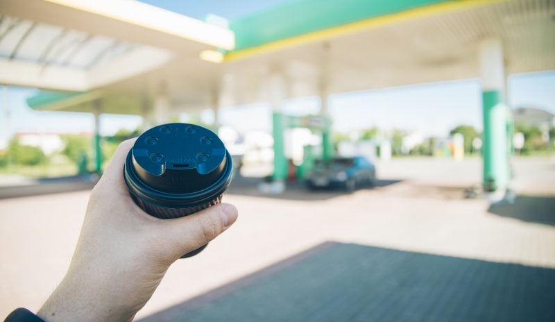 Person holding a small to-go cup in a gas station environment
