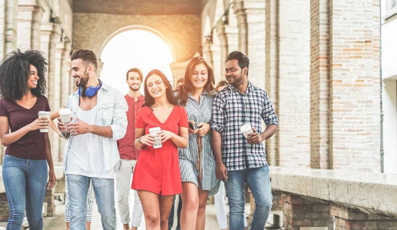 A group of friends walking around their campus, each with a to-go cup