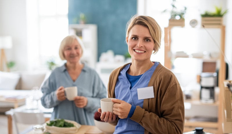 A staff member at a care facility enjoying a cup of coffee with a resident