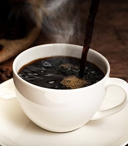 Black, hot coffee being poured into a coffee mug